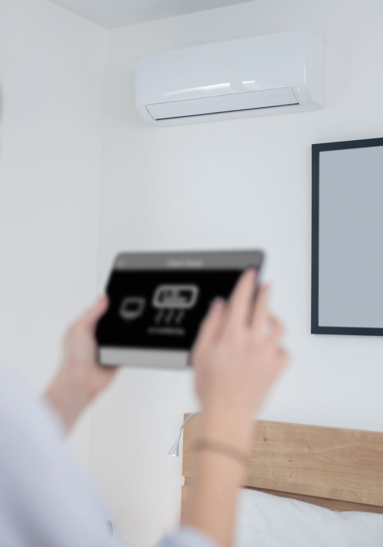 Woman turning on an air conditioner using a tablet